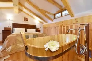 Un bagno caldo nella vasca in legno di ginepro, ti attende al tuo rientro a Maison du Tatà